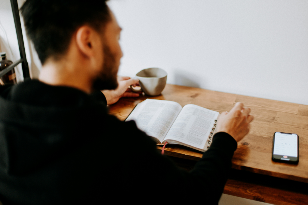 Looking over mans shoulder onto book being read in coffee shop.